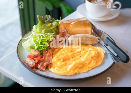 Großes englisches Frühstück mit Speck, Würstchen, Rührei, grünem Salat und Toastbrot. Stockfoto