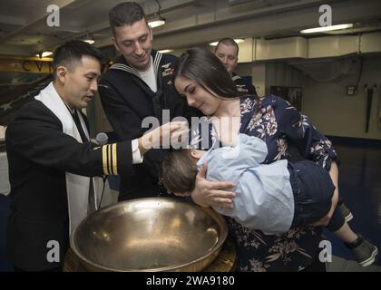 US-Streitkräfte. 180227ZE240-0021 NORFOLK (27. Februar 2018) Lt. Commander. David Kim, Kaplan an Bord des Flugzeugträgers USS Gerald R. Ford (CVN 78), tauft den Sohn von Aviation Boatswain's Mate (Equipment) 1st Class Andrew Holcomb und seinem Verlobten Toni Gray. (Foto der U.S. Navy von Mass Communication Specialist 3rd Class Cat Campbell/veröffentlicht) Stockfoto