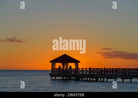 Silhouette eines Stegs vor dem orangefarbenen Himmel in der Abenddämmerung ohne sichtbare Personen, Dominicus Beach, Bayahibe, Dominikanische Republik, Hispaniola, Carib Stockfoto