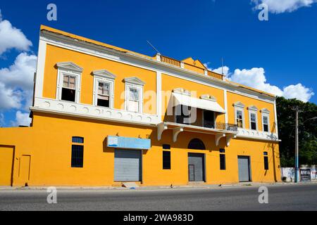 Zweistöckiges gelbes Gebäude unter einem klaren blauen Himmel mit geschlossenen Ladenfronten, Kirche Christi, verbunden mit dem Ministerium, San Pedro de Macoris, Dominica Stockfoto