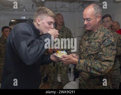 US-Streitkräfte. 181013GR168-1071 ATLANTISCHER OZEAN (13. Oktober 2018) Aviation Boatswain’s Mate (Handling) Airman Apprentice Jared Carter, links, aus Johnson City, Tennessee, isst als jüngster Sailor an Bord des Amphibienschiffs USS New York (LPD 21) als Lt. Merlin Stephan das erste Stück Kuchen, ein Marinekaplan, der dem Combat Logistics Battalion, 24th Marine Expeditionary Unit, dem ältesten Seemann an Bord der New York, zugeteilt ist, hält den Kuchen, der die Weitergabe von Wissen und Erfahrung vom ältesten zum jüngsten Seemann am 13. Oktober 2018 symbolisiert. USS New York (LP Stockfoto