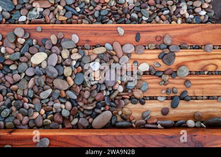 Kieselsteine auf Holztreppen, die von der windigen See bei Flut am Findhorn Beach hochgeworfen werden. Findhorn, Morayshire, Schottland. Stockfoto