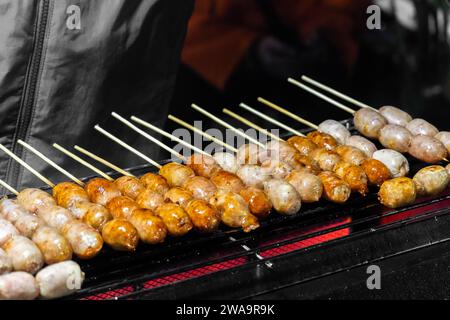 Typische thailändische Isan-Würstchen. Isaan Würstchen. Thailändischer Snack, traditionelle Schweinefleisch- und Reiswürste im nordöstlichen thailändischen Stil (Esan-Würstchen), gegrillt mit Spießen Stockfoto