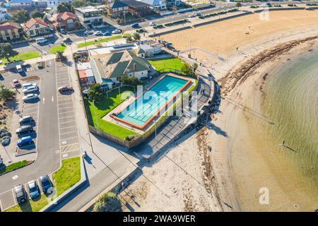 Blick aus der Vogelperspektive auf einen Swimmingpool an der Küste zwischen einem Parkplatz und einem Sandstrand in Williamstown in Melbourne, Victoria, Australien Stockfoto