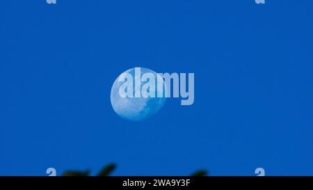 Ein wunderschöner Mond wurde am klaren blauen Himmel gesehen. Nahaufnahme des Mondes in einem hellblauen Himmel. Stockfoto