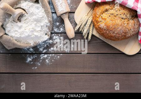 Brot auf Schneidebrett, Mehl und Pin auf hölzernem Hintergrund, Kopierraum Stockfoto