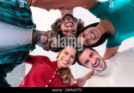 Multirassische Gruppe junger Menschen, die im Kreis stehen und in die Kamera lächeln. Stockfoto