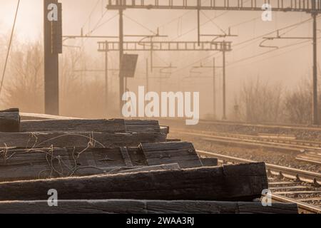 Ein Haufen alter Bahnschwellen vor einem Bahnhof oder Nebengleisen. Alte Schläfer machen Platz für neue. Früher Morgen, nebeliger, nebeliger Morgen Stockfoto