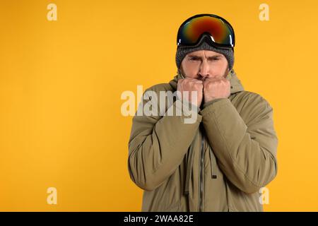 Wintersport. Mann im Skianzug und Schutzbrille auf orangem Hintergrund, Platz für Text Stockfoto