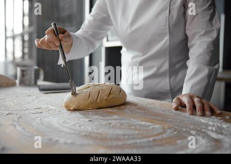 Nahaufnahme weibliche Köchinnen, die Teigschmuck machen, um Brotbrötchen zu dekorieren Stockfoto