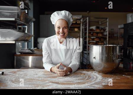 Porträt einer glücklichen Bäckerin mit lächelndem Gesicht in Uniform Stockfoto