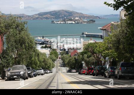Dramatische Aussicht auf Pier 33 und Alcatraz Island, wie man sie von einer steilen Straße in der Innenstadt von San Francisco aus über die Bucht von San Francisco sieht Stockfoto