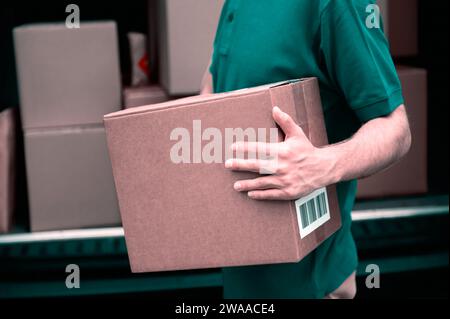 Liefermann mit Pappkartons. Online-Shopping und Expresszustellung. Kopierbereich. Der Mann hält eine große Kiste in den Händen Stockfoto