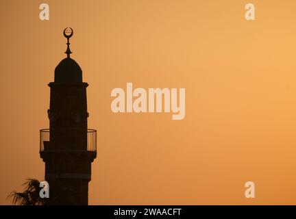 Eine fesselnde Silhouette des Minaretts der Al-Bahr Moschee vor einem warmen Sonnenuntergangshimmel in Tel-Aviv, Israel. Stockfoto