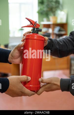 Mitarbeiter halten einen Feuerlöscher im Büro. Das Konzept des Brandschutzes Stockfoto