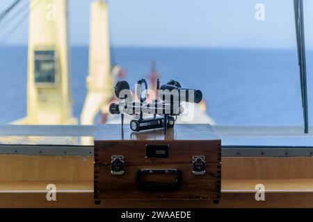 Nautischer schwarzer Sextant auf Holzkiste in der Navigationsbrücke. Navigationsausrüstung. Himmlische Navigation. Stockfoto