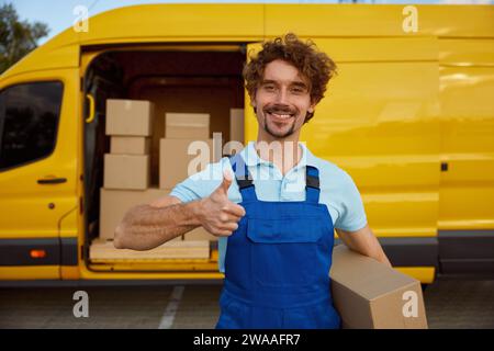 Porträt eines glücklichen, zufriedenen Kuriers mit Daumensuppen wie Geste Stockfoto