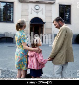 Eltern der 1960er Jahre. Mutter und Vater begleiten ihre Tochter an ihrem ersten Schultag. 1969 Stockfoto