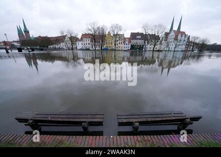 Lübeck, Deutschland. 03. Januar 2024, Schleswig-Holstein, Lübeck: Parkbänke stehen am Ufer der überfluteten Trave in der Innenstadt. Teile der Trave haben ihre Banken bereits geplatzt. Die Hansestadt Lübeck hat am Mittwoch vor der Überschwemmungsgefahr in Teilen der Innenstadt gewarnt. Laut Prognosen soll der Wasserstand, wie die Stadt mitteilte, um 11,00 Uhr um 1,05 Meter über dem Meeresspiegel steigen. Foto: Marcus Brandt/dpa Credit: dpa Picture Alliance/Alamy Live News Stockfoto