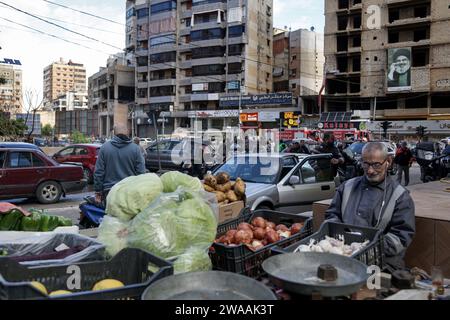 Beirut, Libanon. Januar 2024. Ein Gemüseverkäufer wartet auf Kunden außerhalb des Gebiets, in dem das palästinensische Büro der Hamas (ganz links) am 2. Januar von Israel angegriffen wurde und der palästinensische Führer Saleh al-Arouri und sechs weitere im südlichen Vorort Beiruts getötet wurden. Quelle: Marwan Naamnai/dpa/Alamy Live News Stockfoto