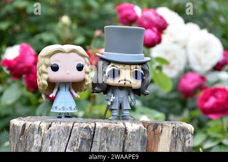 Funko Pop Actionfiguren von Alice im Wunderland aus Tim Burton Fantasy-Film und Bram Stokers Dracula Vampirprinz Vlad. Rote und weiße Rosen. Stockfoto