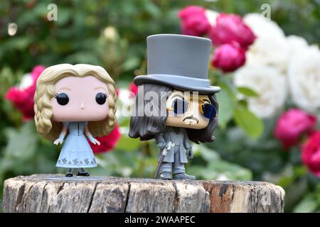 Funko Pop Actionfiguren von Alice im Wunderland aus Tim Burton Fantasy-Film und Bram Stokers Dracula Vampirprinz Vlad. Rote und weiße Rosen. Stockfoto