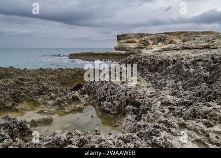 Poetry Cave (Grotta della Poesia) Naturpool umgeben von zerklüfteten Kalksteinklippen mit Höhlen und einem Tunnel zum offenen Meer. Apulien, Italien Stockfoto