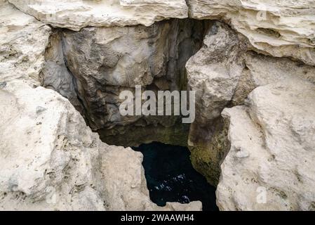 Poetry Cave (Grotta della Poesia) Naturpool umgeben von zerklüfteten Kalksteinklippen mit Höhlen und einem Tunnel zum offenen Meer. Apulien, Italien Stockfoto