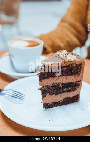 Vertikales Bild einer nicht erkennbaren Frau, die Kuchen isst und Kaffee trinkt, für soziale Netzwerke des Café- und Konditorkonzepts Stockfoto