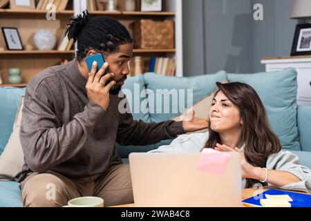 Junge freischaffende gemischte Rassen-Paar Kleinunternehmer, die im Heimbüro an einem Laptop arbeiten, Probleme mit der Internetverbindung oder Firmen-Web-pag Stockfoto