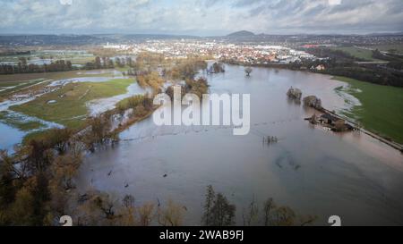 03. Januar 2024, Hessen, Fulda: Die stark aufgestiegene Fulda ist im Bezirk Bronnzell über die angrenzenden Wiesen geplatzt. Im Hintergrund ist die Stadt Fulda zu sehen. Nach den starken Regenfällen am Mittwoch und am Donnerstagabend platzen Flüsse und Bäche in Osthessen, einschließlich der Fulda, am Ufer. An der Messstation im Fuldaer Stadtteil Bronnzell stieg das Niveau der Fulda sogar über die dritte Meldeebene, wo es nach Angaben des Landesamtes zu außergewöhnlichen Überschwemmungen kommt. (Foto mit einer Drohne) Foto: Andreas Arnold/dpa Stockfoto