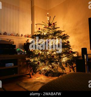 Weihnachtsbaum in einem britischen Wohnzimmer, dekoriert für Weihnachten. Leuchten leuchten. Stockfoto
