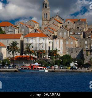 Der campanile der Markusdom erhebt sich über roten Dächern in der Stadt Korčula im kroatischen Komitat Dubrovnik-Neretva. In diesem Bild ist auch die Spitze des westlichen Giebels der Kathedrale zu sehen, dessen prächtige Dekoration in den späten 1400er Jahren hinzugefügt wurde Stockfoto