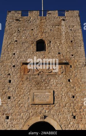 Ravelin Tower über dem Haupttor der Stadt Korčula, Komitat Dubrovnik-Neretva, Kroatien. Der Turm wurde in den 1400er Jahren erbaut und ist mit einem geflügelten Löwen des hl. Markus, Symbol der Republik Venedig, unter den Vorderpfoten des Markusevangeliums verziert. Stockfoto