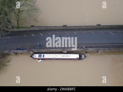 Barrow upon Soar, Leicestershire, Großbritannien. Januar 2024. Wetter in Großbritannien. Ein schmales Boot wird an einer Brücke gefangen, nachdem es sich von seiner Anlegestelle am Fluss Soar befreit hat. Heftiger Regen hat einen großen Teil Großbritanniens heimgesucht, als der kleine, aber potente Sturm Henk traf. Credit Darren Staples/Alamy Live News. Stockfoto