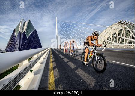 Radfahrer, die während eines Triathlons auf der modernen Brücke der Stadt der Künste und Wissenschaften in Valencia antreten und Sport und Architektur miteinander verbinden Stockfoto