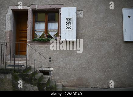 Malerische lokale elsässische Hausfassade mit einer Holztür und einem Fenster mit festlicher Weihnachtsdekoration in Dambach-la-Ville, Frankreich. Stockfoto