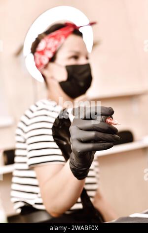 Frau, die die Tätowiermaschine in der Hand hält. Kunst- und Designkonzept. Nahaufnahme Stockfoto