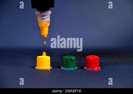 Gelbe Tinte tropft in kleinen Kunststoffbecher. Kunst- und Designkonzept. Nahaufnahme Stockfoto