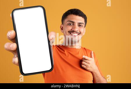 Fröhlicher Mann, der ein großes Handy mit weißem, leerem Bildschirm zeigt Stockfoto