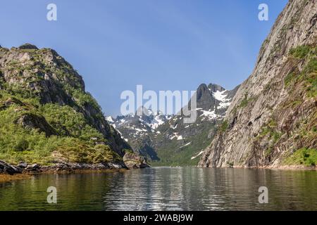 Das ruhige Wasser des Trollfjordens bildet einen perfekten Spiegel für die hoch aufragenden Klippen und schneebedeckten Berge unter dem hellen nordischen Himmel. Lofoten Stockfoto