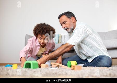 Großvater und Enkel spielen in der Montage der Spielzeugbahn im Haus Stockfoto