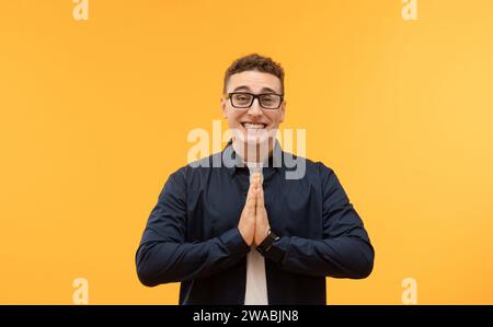 Flehender junger Mann mit gefalteten Händen im Gebet Stockfoto