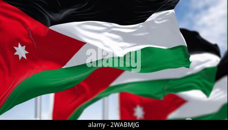 Jordan Nationalflaggen winken an klaren Tagen im Wind. Schwarze, weiße und grüne horizontale Streifen mit einem roten Chevron auf der linken Seite mit einem weißen sev Stockfoto