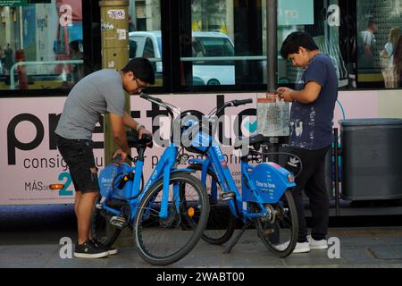 Barcelona, Spanien - 26. Mai 2022: Zwei Teenager asiatischer Herkunft sind dabei, den Elektrofahrraddienst über die Handy-App zu nutzen. Stockfoto