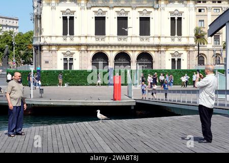 Barcelona, Spanien - 26. Mai 2022: Zwei Zwillinge arabischer Herkunft werden zusammen im Hafen fotografiert, zwischen den beiden ist eine Möwe ruhig und ruhig. Stockfoto