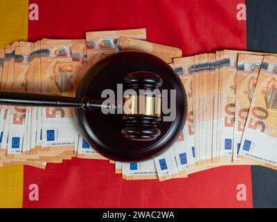 Der Hammer des Richters liegt auf 50-Euro-Scheinen vor dem Hintergrund der deutschen Flagge. Recht und Gerechtigkeit. Stockfoto