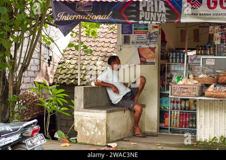 Die Menschen ruhen sich in einem ungewöhnlichen asiatischen Dorf in der Nähe der Straße aus. Kinder spielen und Erwachsene sprechen am Straßenrand. Bali, Indonesien - 12,16 Stockfoto