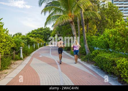 Ein junger Mann überholt einen Fußgänger während eines Workouts entlang der Walking Street in Miami Beach an einem hellen Sommertag. Miami Beach. USA. Stockfoto