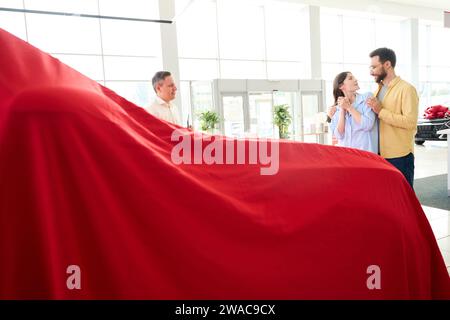 Der Kundendienstleiter präsentiert das Fahrzeug unter einem Geschenketui Stockfoto